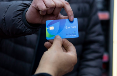 A man passes a British Gas top-up card to another person