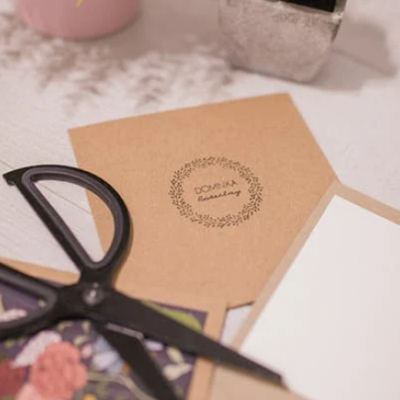 A brown gift card with a pair of black scissors