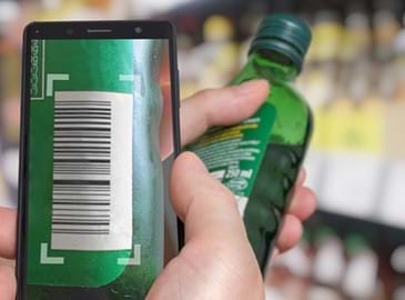 A retail employee scans a bottle of alcohol